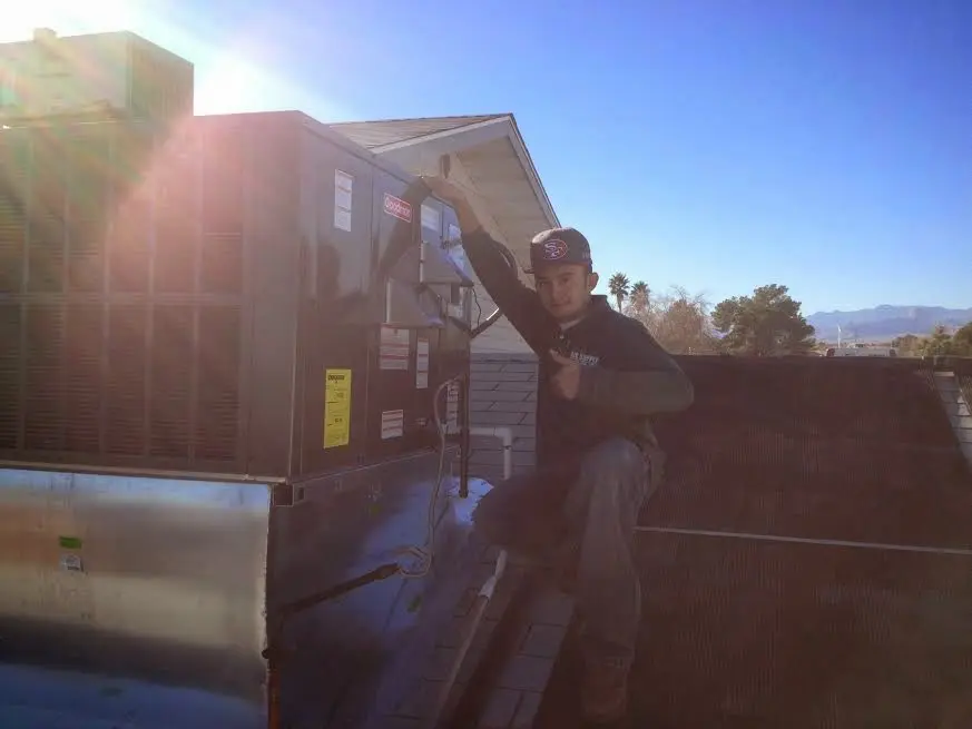 HVAC technician performing Air Duct Cleaning on a rooftop unit in Lorton