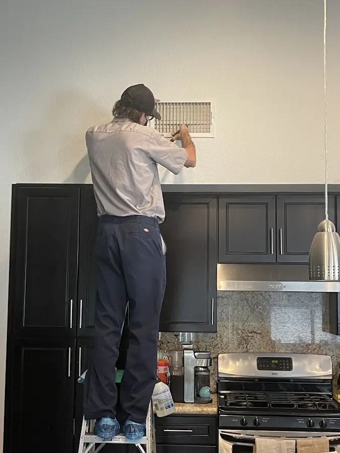Technician inspecting an air vent during HVAC service in Lorton
